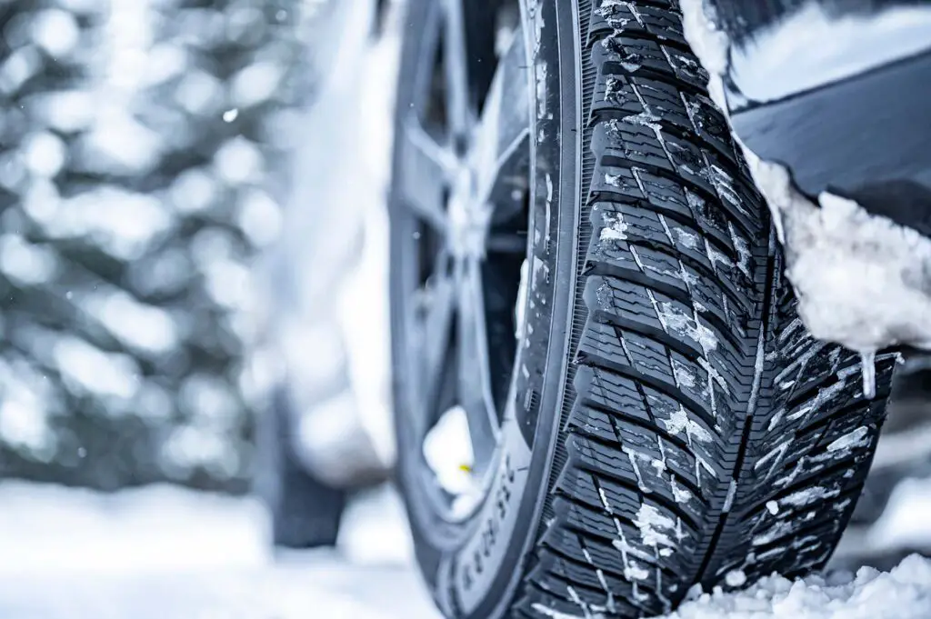 A close-up of a car tire in snowy weather
