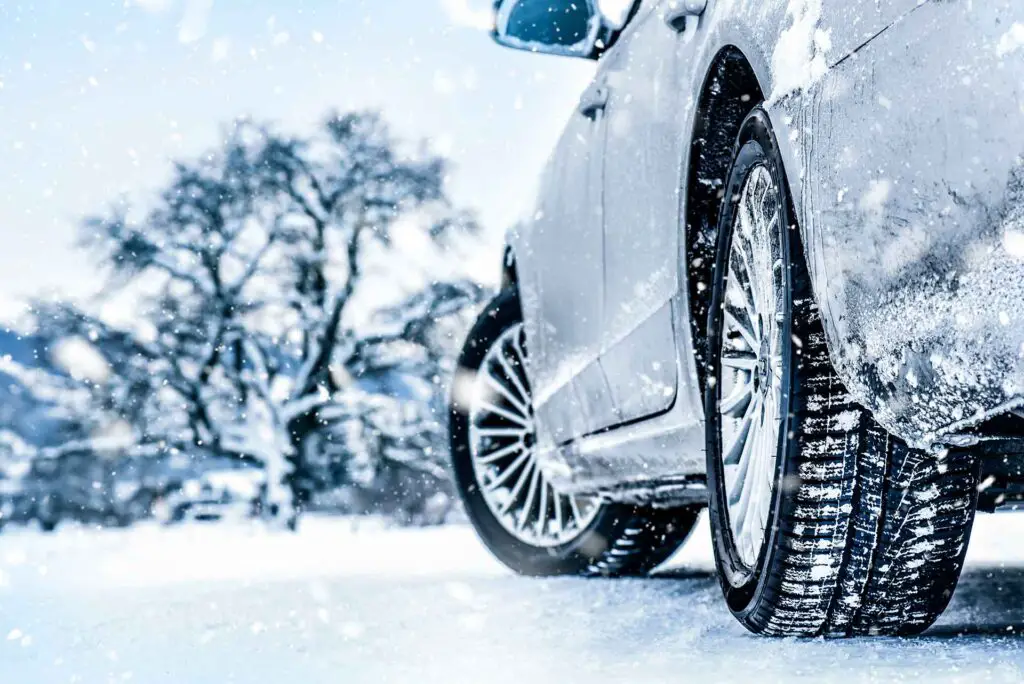 A close-up of a car's winter tire on a snowy background