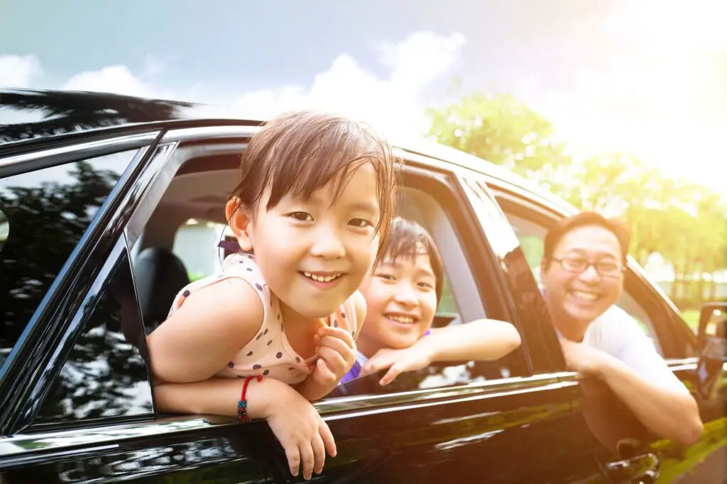 happy little girl with family sitting in the car