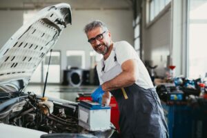 worker changing battery in car service