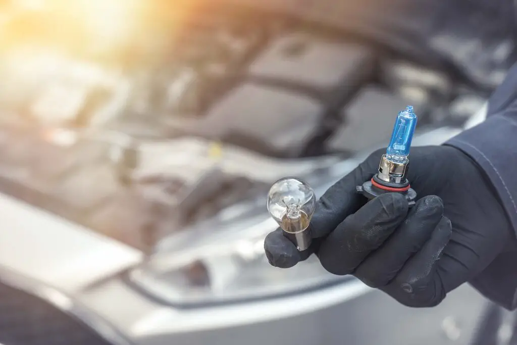 A person holding the light bulb of a car headlight