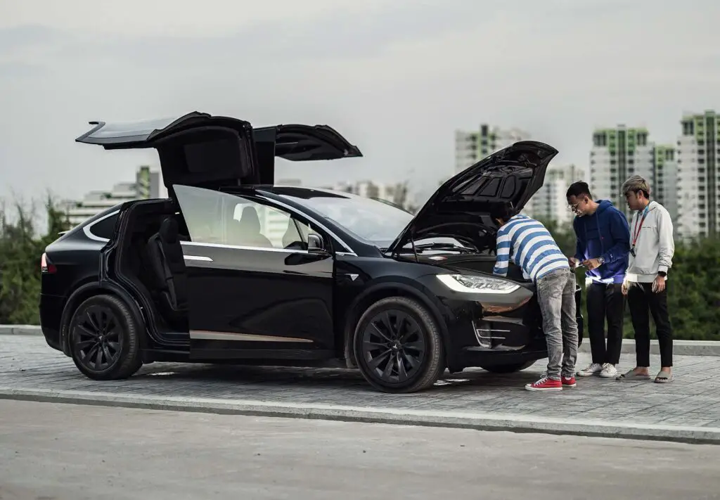 People looking under the hood of a Tesla Model X