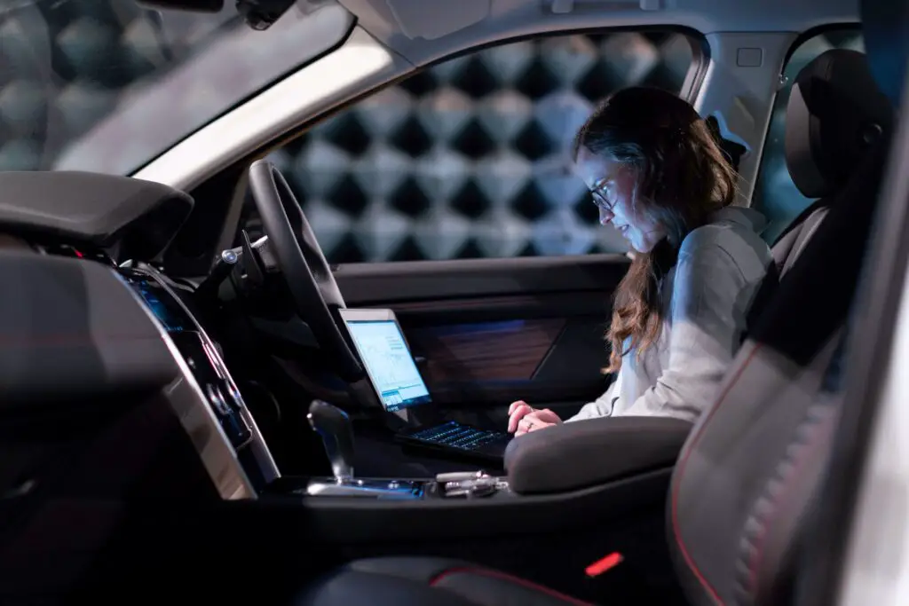 Woman sitting in a car with a laptop
