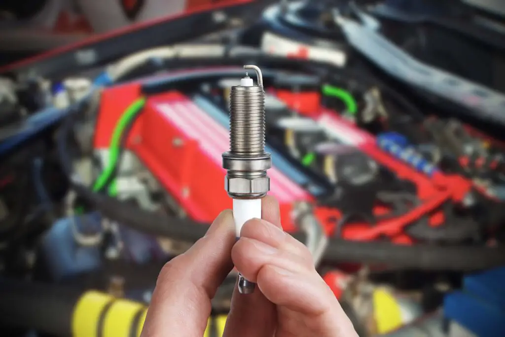  Mechanic holds a spare part spark plug in his hand