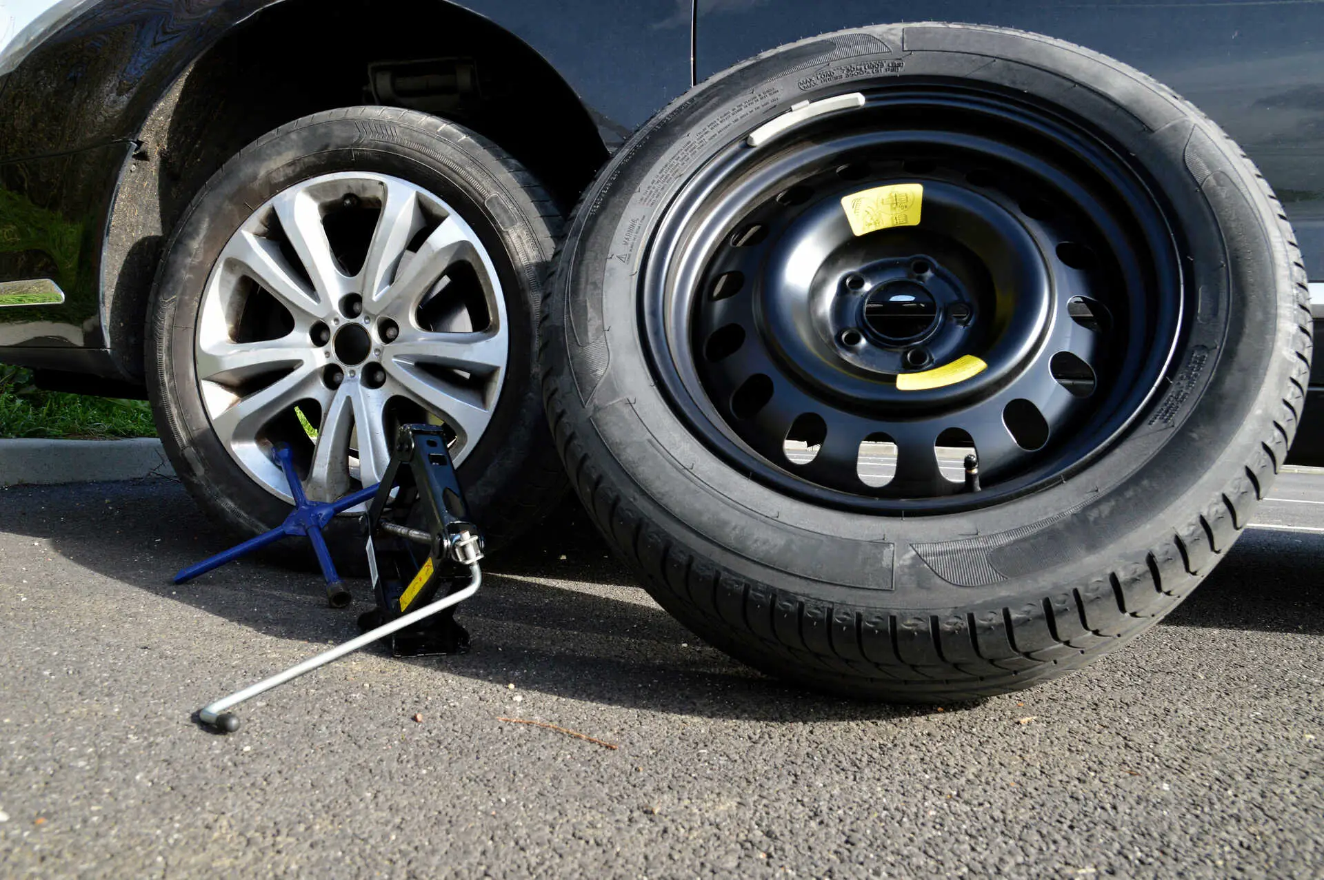 Tire change with aluminum rim and spare tire following a puncture, with a lug wrench and jack