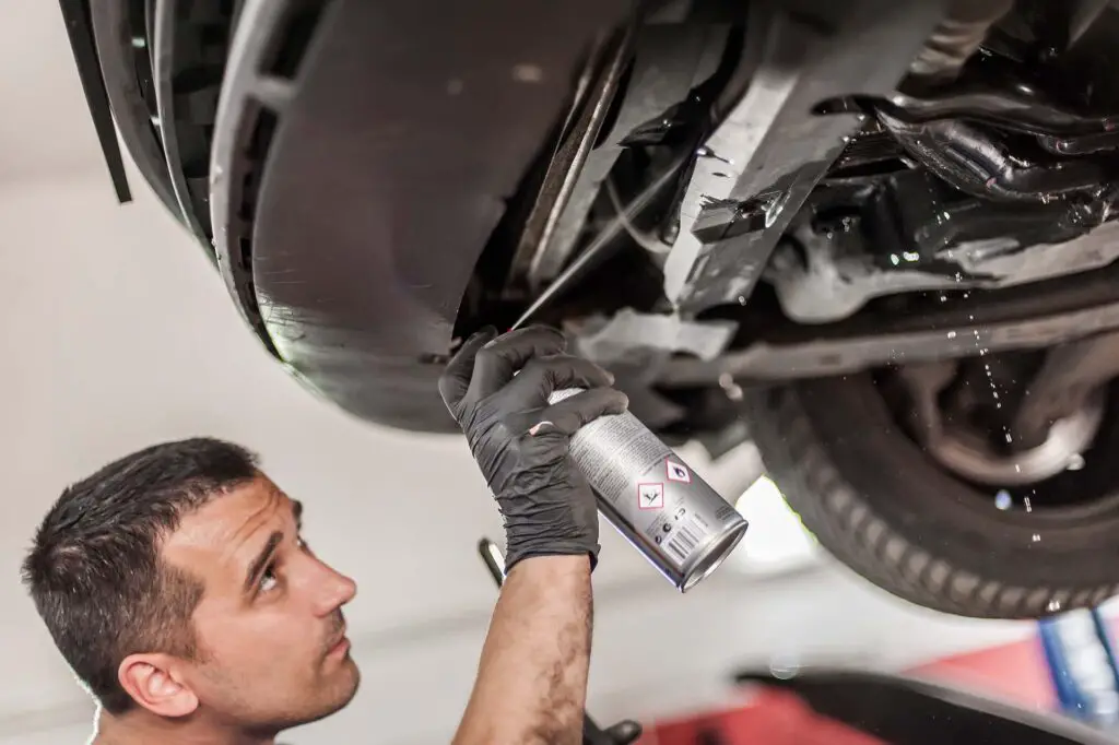 A mechanic lubricates car screws