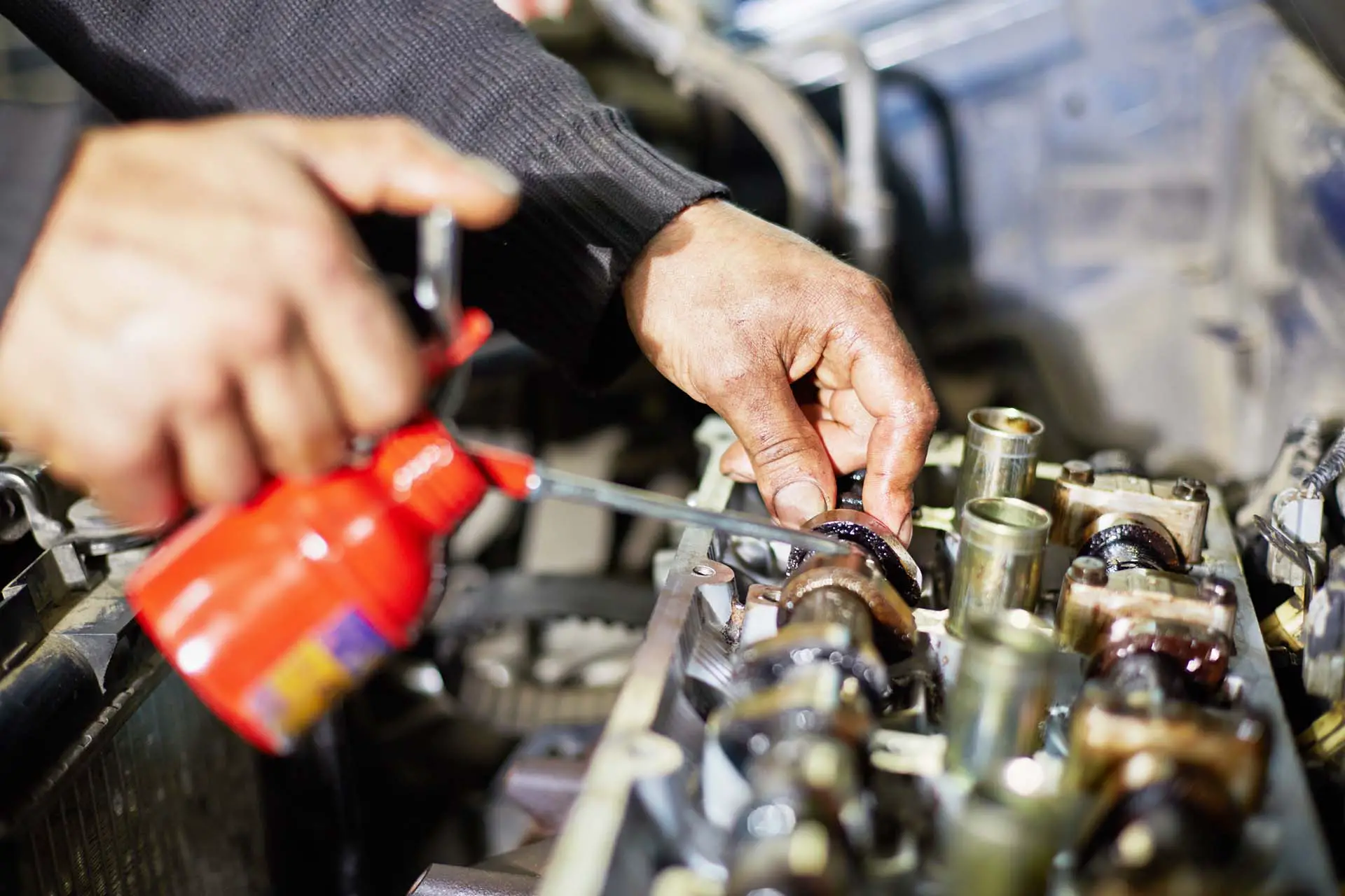 Hands of mechanic, who lubricates car engine