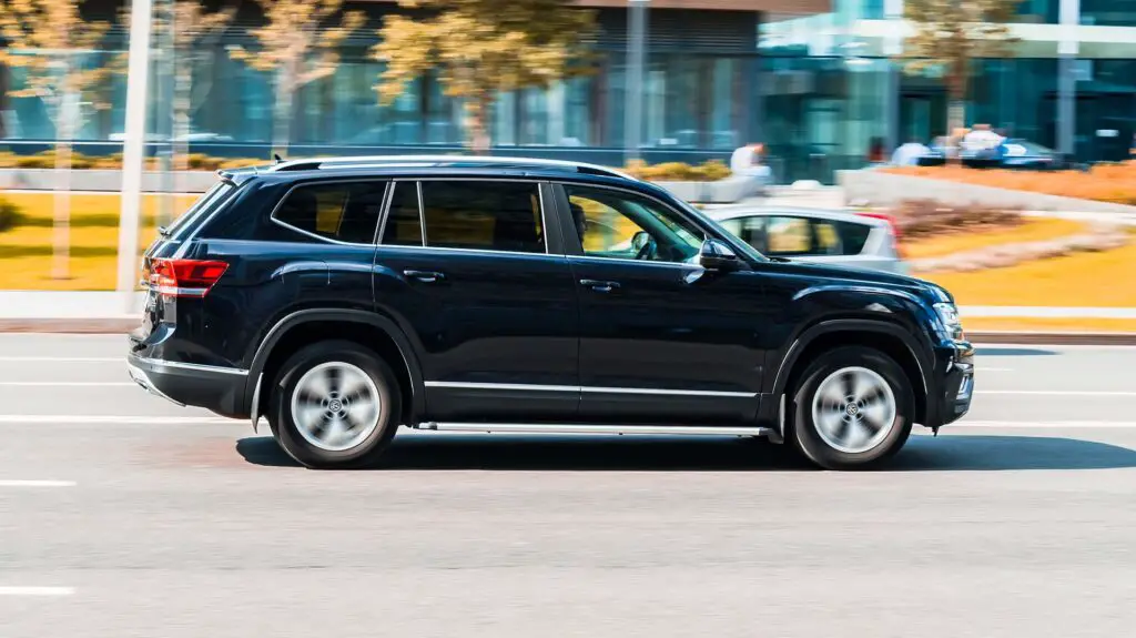 Black Volkswagen Atlas is driving along the street with an autumn urban background. Volkswagen Teramont is a mid-size crossover SUV manufactured by VW