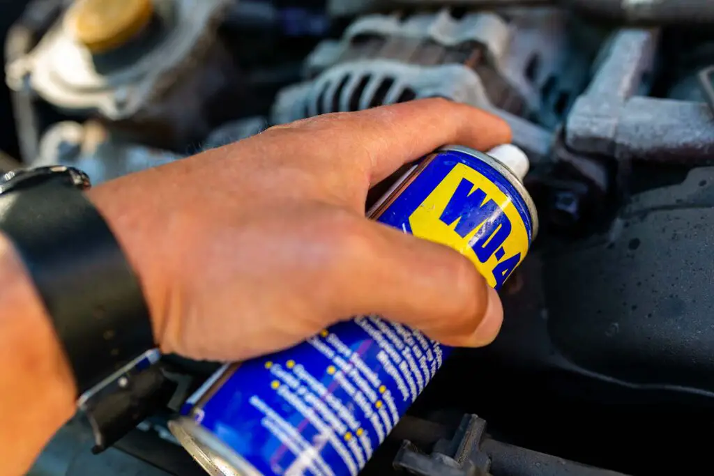 Mechanic using WD-40 multi-purpose oil to loosen a tight bolt