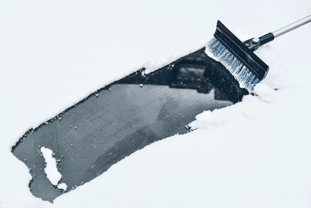 A brush on a car windshield covered with snow