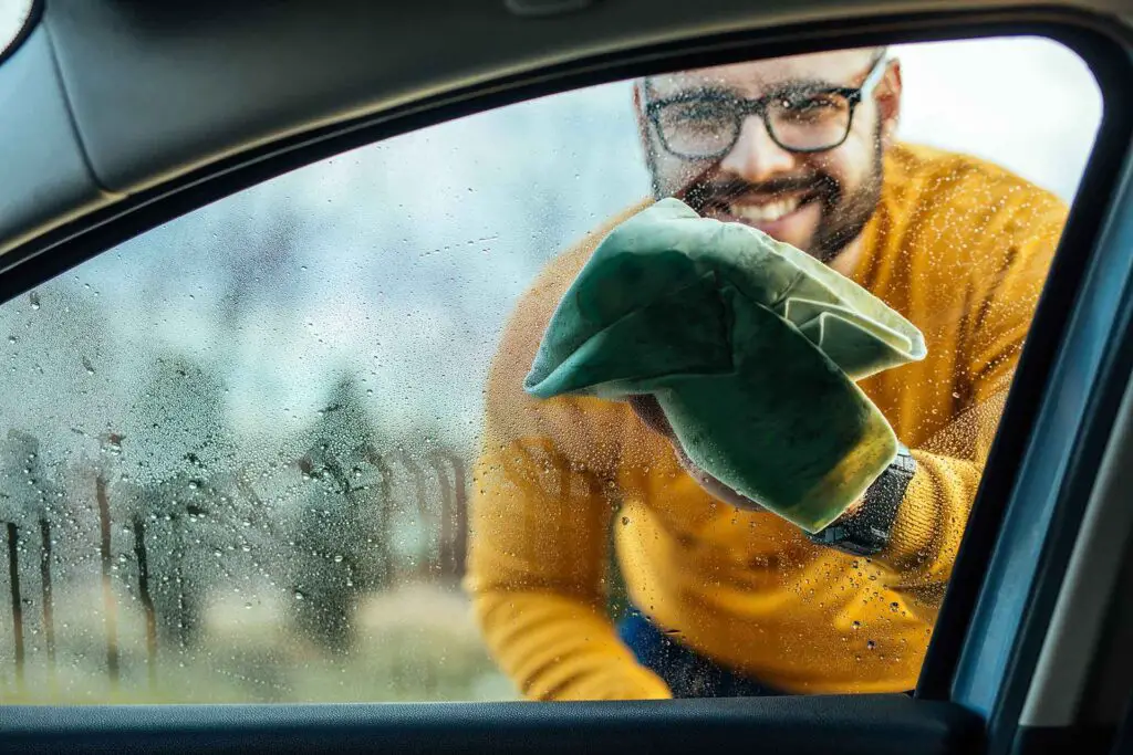 A man cleaning a car window