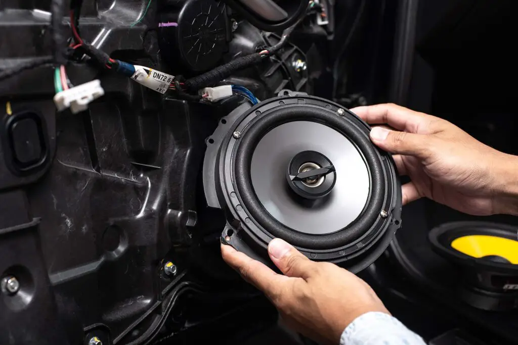 Technician installing the car speaker to the car door. Car audio installation concept.