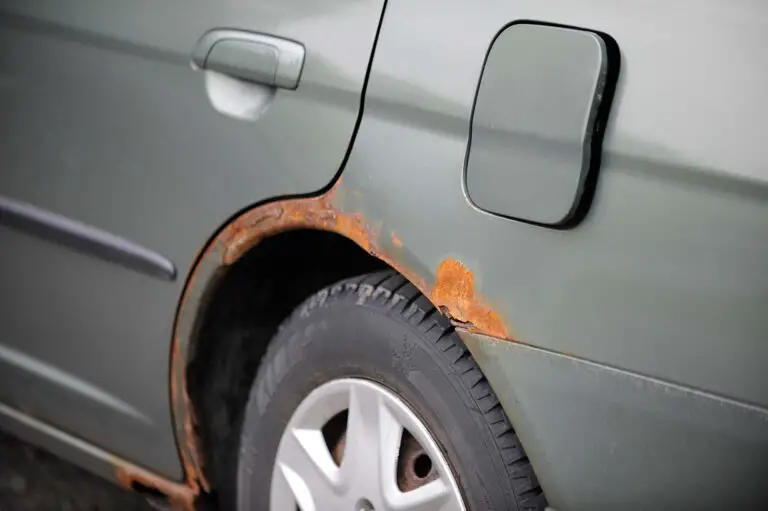 A gray car with rust around the wheels