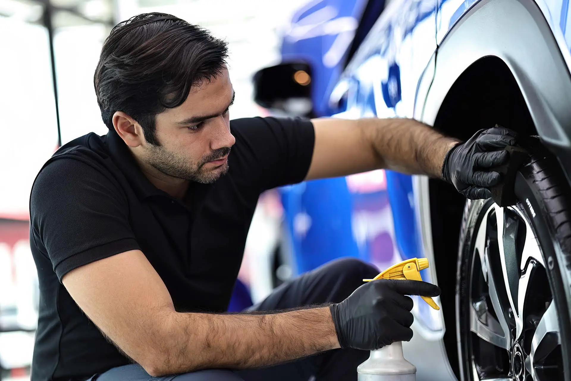 Car service worker polishing car wheels with microfiber cloth an