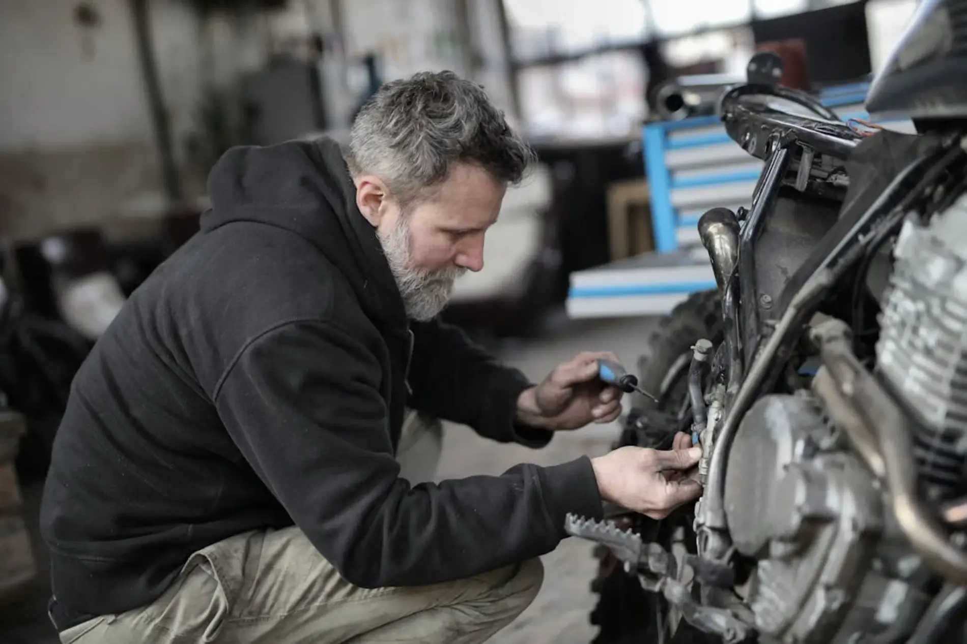 Bearded man fixing motorcycle in the workshop