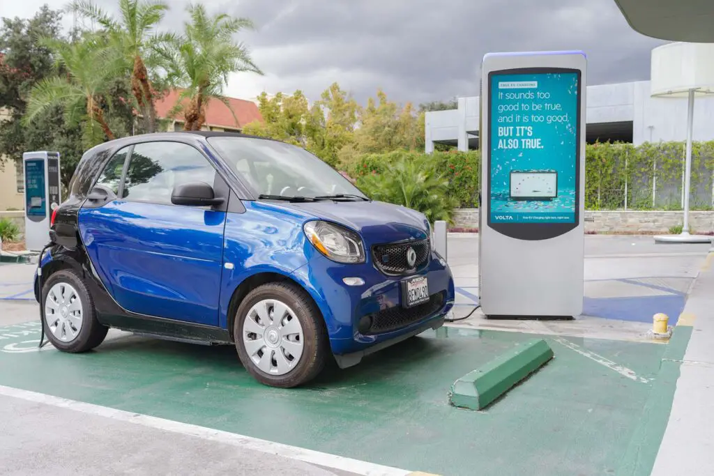 image of a Smart EQ fortwo vehicle shown at a free charging station. Smart is a German automotive brand.