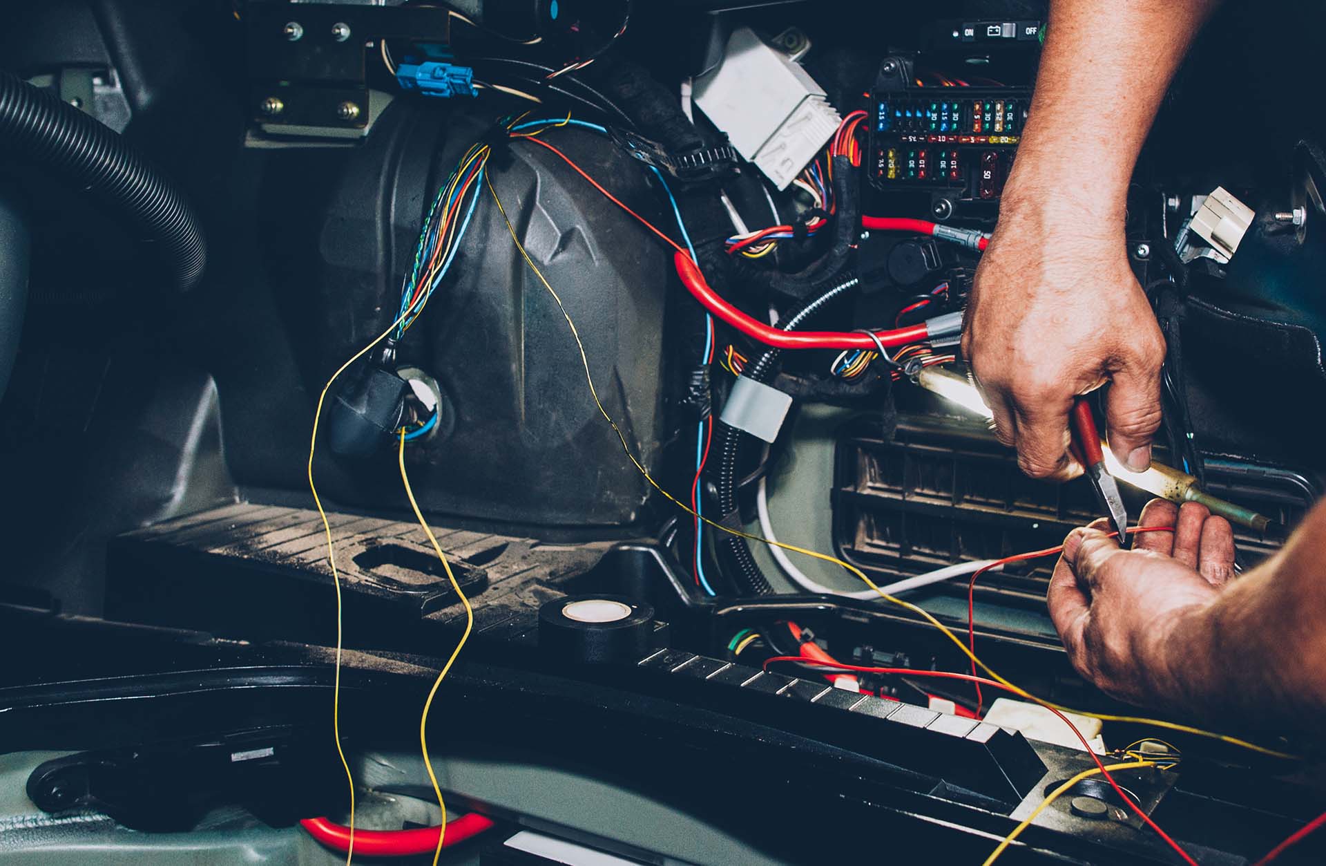 Mechanic electrician checking repairing upgrading wiring. Auto service workshop. Regular preventive car maintenance.