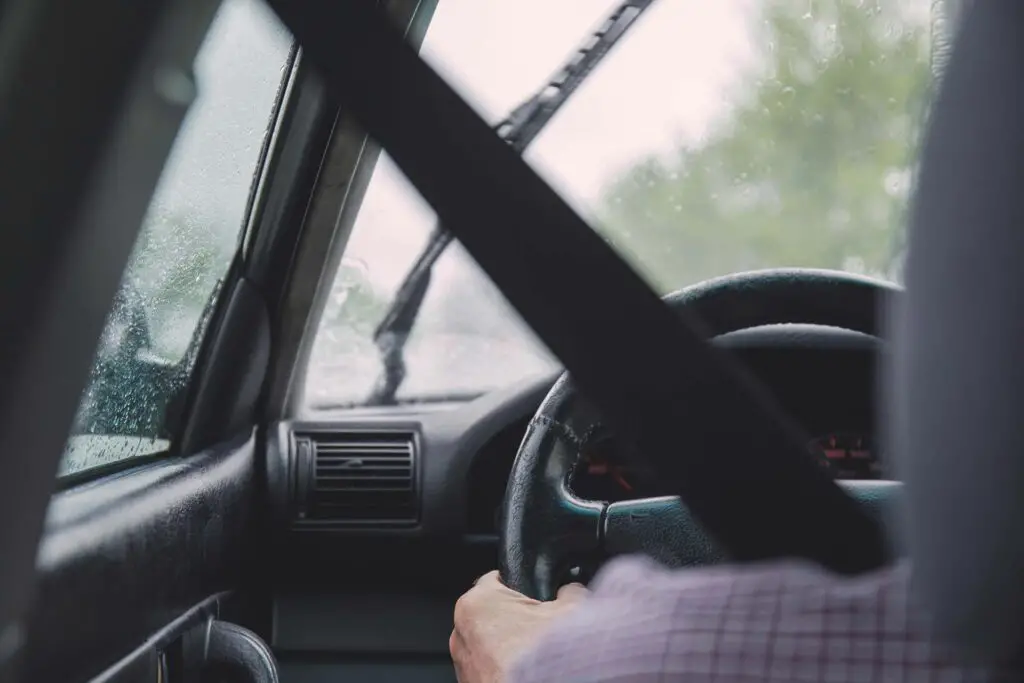 A person driving a car while wearing a seatbelt