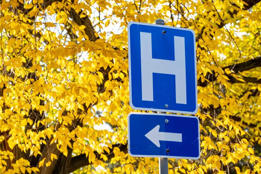 A blue "H" road sign with an arrow shows the direction of a hospital.