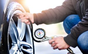 Detail of inflating tire and checking air pressure use gauge in mechanics hands.