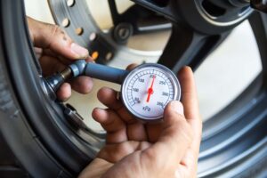 Hand holding pressure gauge for motorbike tyre pressure measurement