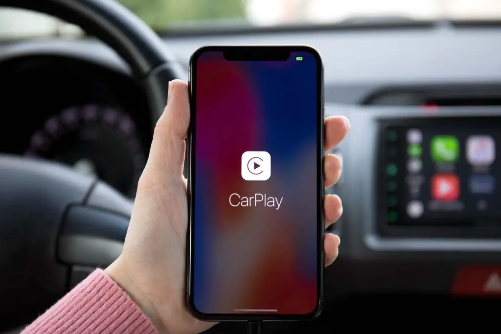 Woman hand holding iPhone X with CarPlay on the screen in the car. iPhone 10 was created and developed by the Apple inc.