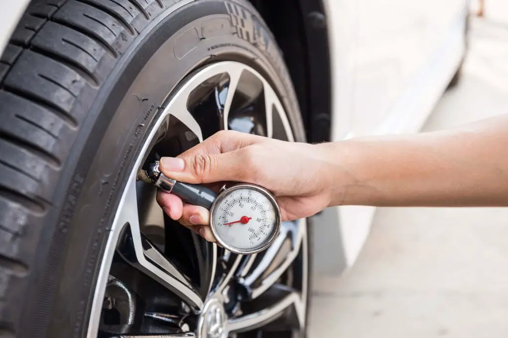 Close-Up Of Hand holding pressure gauge for car tyre pressure measurement