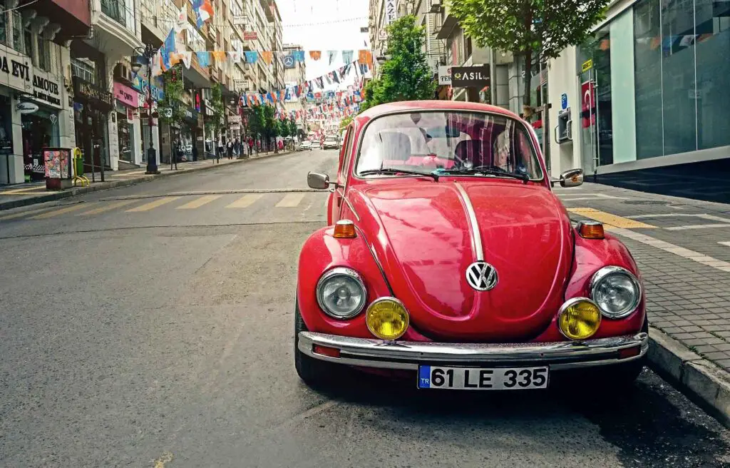 A red older model of Volkswagen Beetle parked on the street