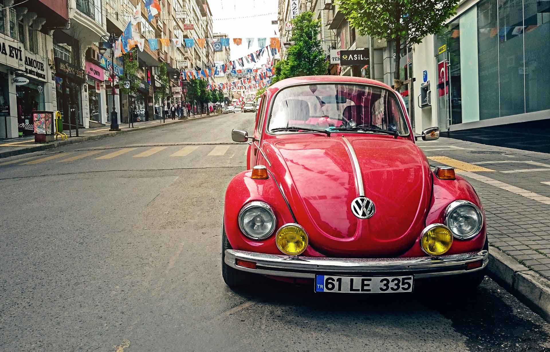 A red older model of Volkswagen Beetle parked on the street