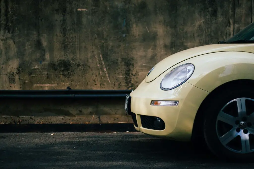 The front of a yellow modern Volkswagen Beetle