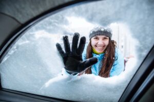 young woman clean car of snow view from inside