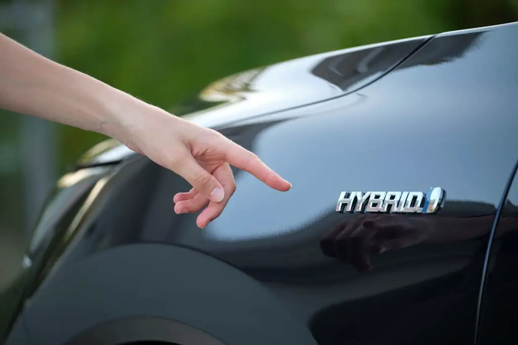 Human hand showing hybrid car sign on new effective vehicle.