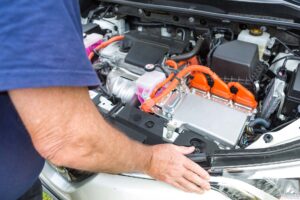 Senior man leaning over the interior of a hybrid car powered both by electric battery and gas engine