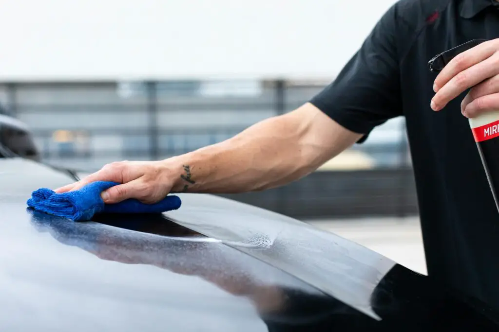 A man cleaning a car with a spray