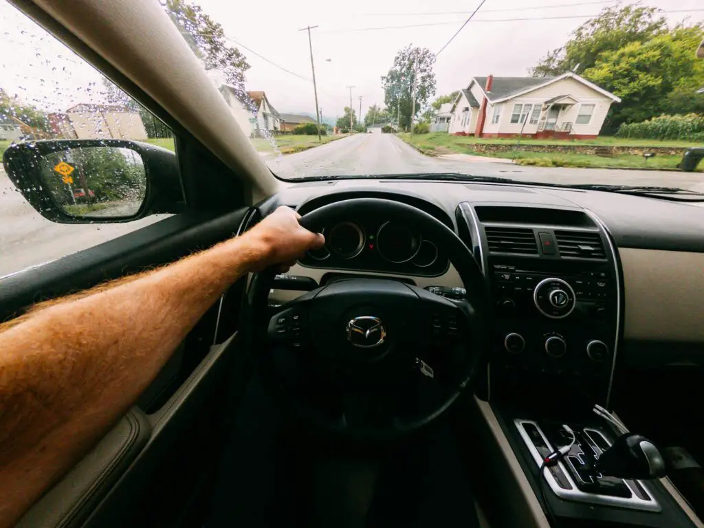 A man driving a manual Mazda car