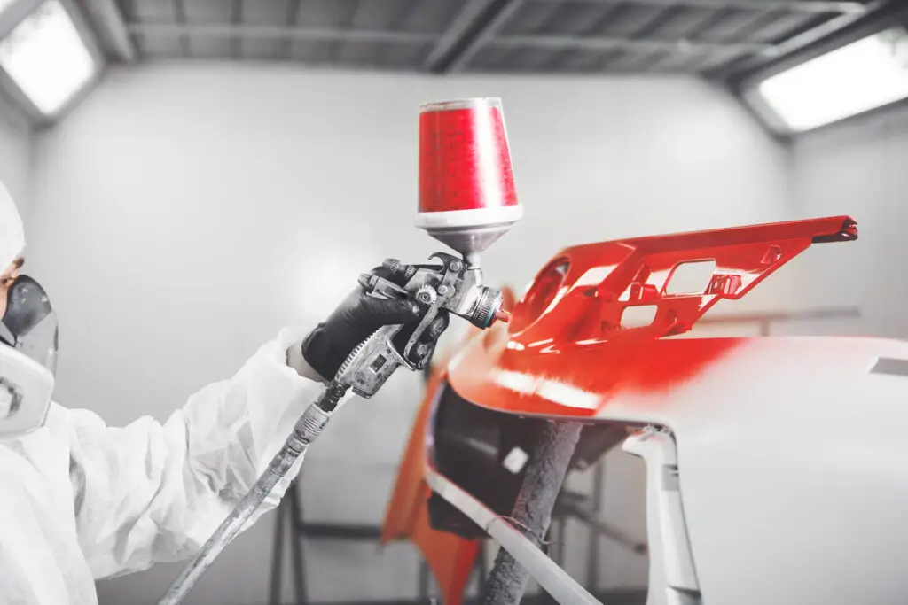 Spray painter painting the car in red